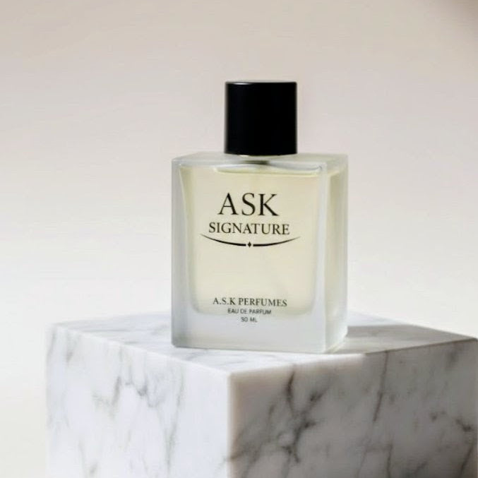 Perfume bottle labeled 'ASK Signature' on a marble surface with a neutral background